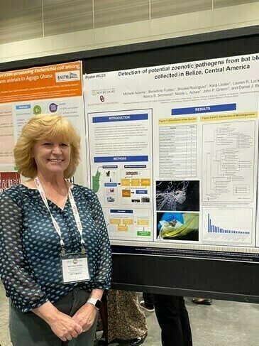 Woman looking at camera in front of a scientific poster.